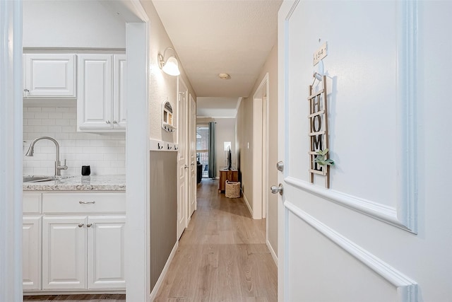 corridor featuring light wood-type flooring and sink