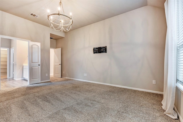 carpeted empty room with vaulted ceiling and a notable chandelier