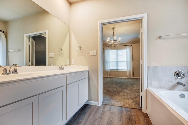 bathroom featuring a chandelier, vanity, hardwood / wood-style flooring, and a washtub