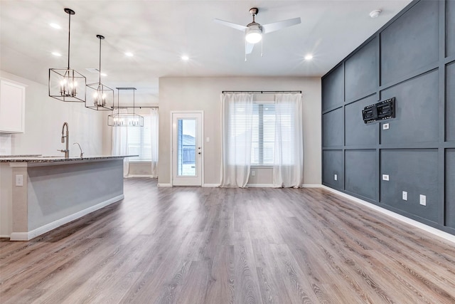 interior space featuring light stone countertops, ceiling fan, sink, decorative light fixtures, and hardwood / wood-style flooring