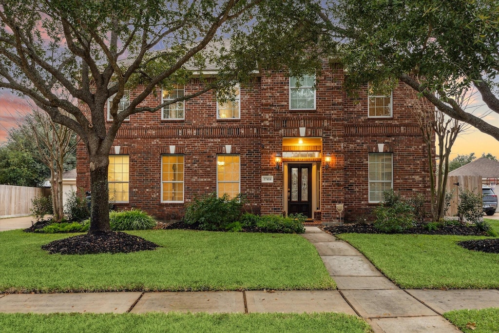 colonial-style house featuring a lawn and french doors