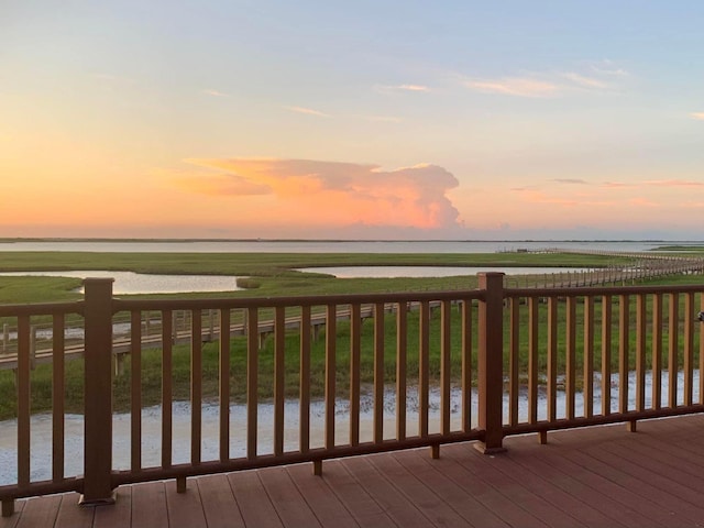 deck at dusk featuring a water view