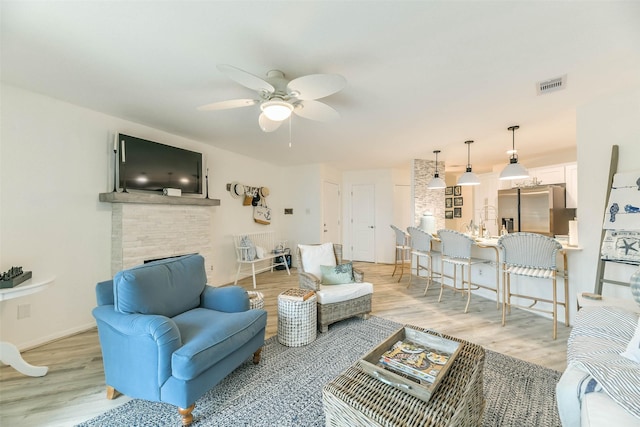 living room with ceiling fan, light hardwood / wood-style flooring, and a fireplace