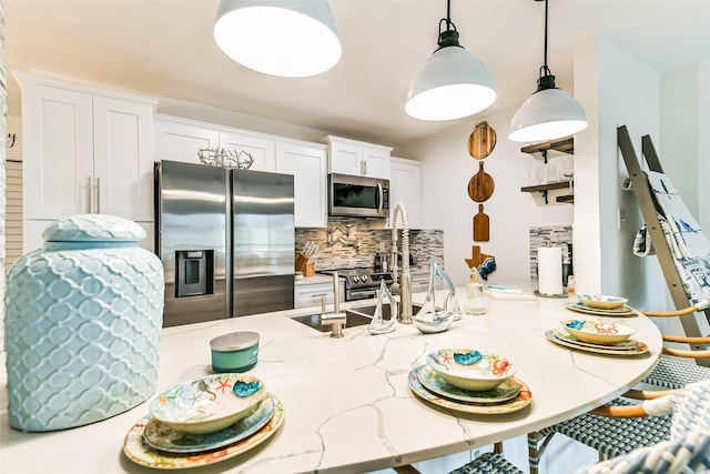 kitchen with light stone counters, decorative light fixtures, decorative backsplash, white cabinets, and appliances with stainless steel finishes