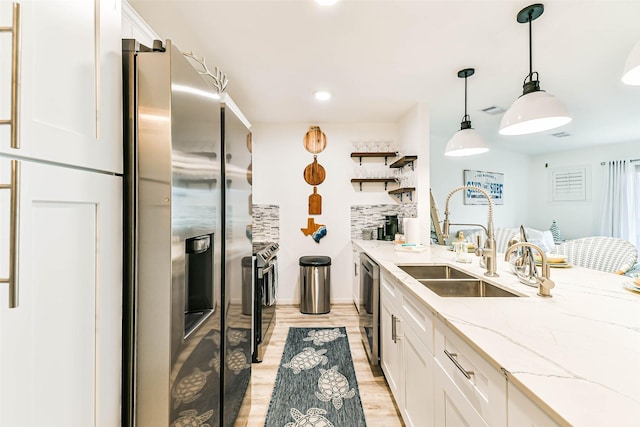 kitchen featuring sink, white cabinets, pendant lighting, and appliances with stainless steel finishes