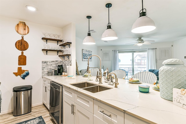 kitchen featuring white cabinetry, dishwasher, hanging light fixtures, and sink