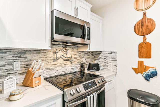 kitchen featuring light stone counters, appliances with stainless steel finishes, tasteful backsplash, and white cabinetry