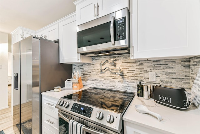 kitchen featuring white cabinets, appliances with stainless steel finishes, and backsplash