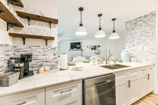 kitchen with stainless steel dishwasher, decorative backsplash, sink, and light stone countertops