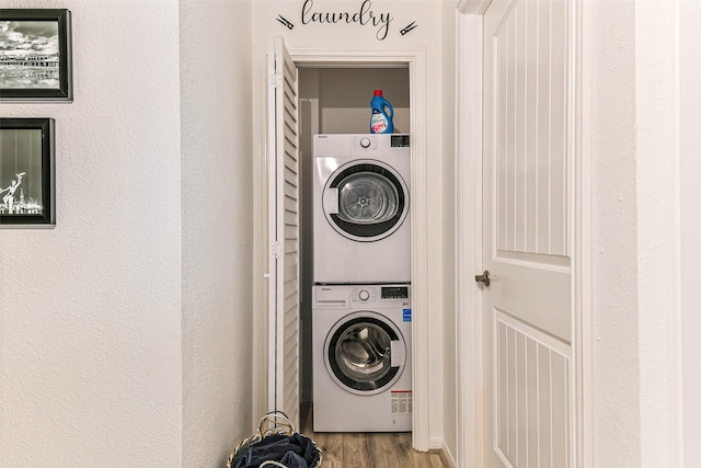 laundry room featuring wood-type flooring and stacked washer and dryer