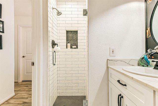 bathroom featuring a tile shower, wood-type flooring, and vanity