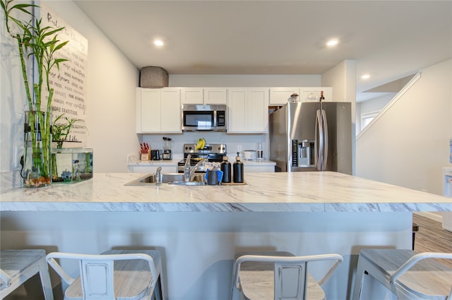 kitchen with a breakfast bar, appliances with stainless steel finishes, white cabinets, and sink