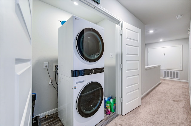 clothes washing area with stacked washing maching and dryer and light carpet