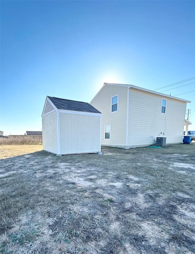 back of house with a storage unit and central AC