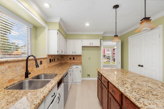 kitchen with backsplash, sink, dishwasher, white cabinetry, and hanging light fixtures