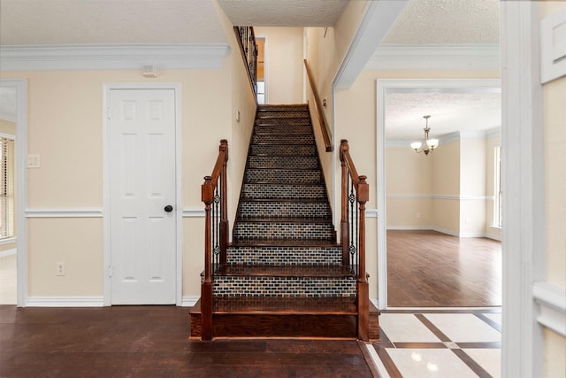 stairs with hardwood / wood-style flooring, crown molding, a textured ceiling, and a chandelier