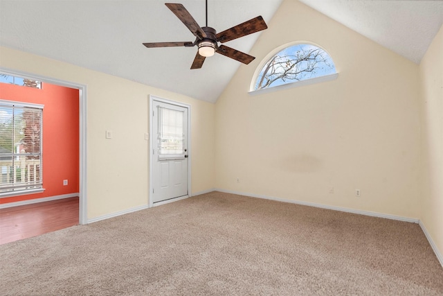 carpeted spare room with ceiling fan and high vaulted ceiling