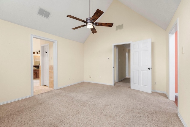 unfurnished bedroom featuring ceiling fan, high vaulted ceiling, ensuite bathroom, and light carpet