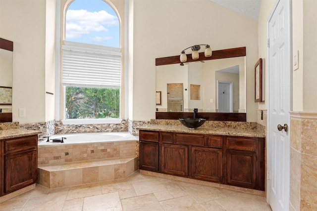 bathroom featuring vanity, a relaxing tiled tub, and lofted ceiling