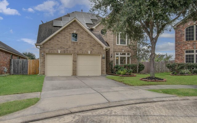 view of property featuring solar panels, a garage, and a front lawn