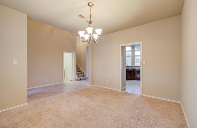 spare room featuring light colored carpet and a notable chandelier