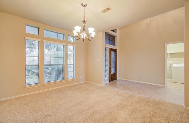 empty room featuring washer / clothes dryer, a notable chandelier, and light colored carpet