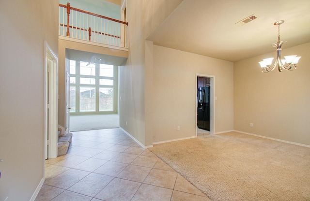 entryway with a towering ceiling, light tile patterned floors, and a notable chandelier