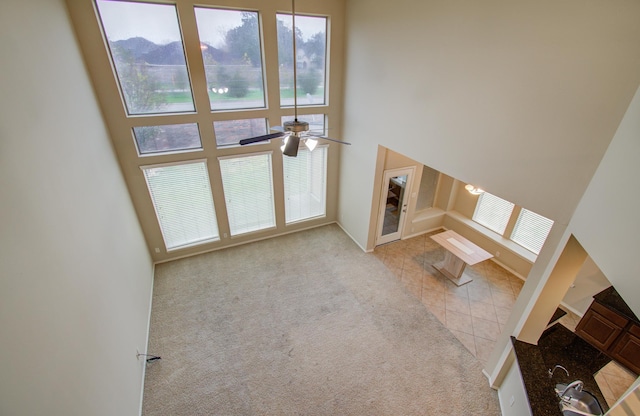 unfurnished living room with light carpet, a wealth of natural light, and a high ceiling