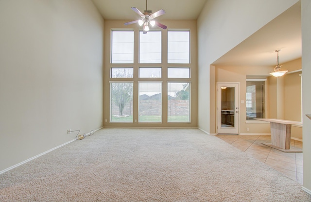 unfurnished living room with light carpet, a high ceiling, and ceiling fan