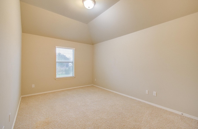 carpeted spare room featuring lofted ceiling