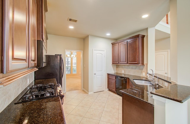 kitchen with dark stone counters, sink, light tile patterned floors, and black appliances