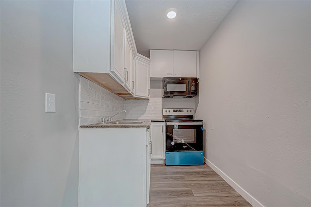 kitchen featuring stainless steel electric stove, decorative backsplash, white cabinets, and light wood-type flooring