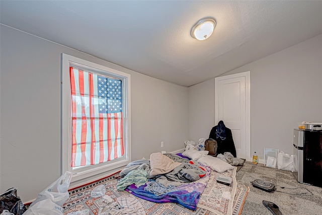 bedroom featuring stainless steel fridge, lofted ceiling, and multiple windows