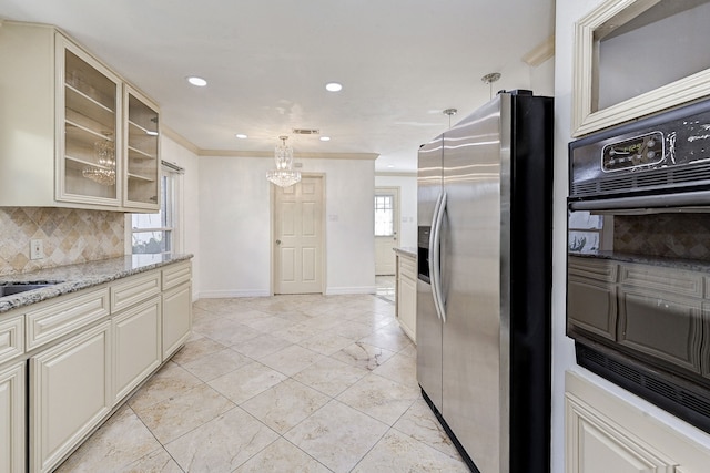 kitchen featuring tasteful backsplash, light stone counters, decorative light fixtures, stainless steel fridge, and cream cabinetry