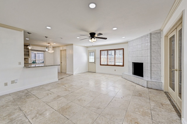 unfurnished living room featuring crown molding, a tile fireplace, and ceiling fan