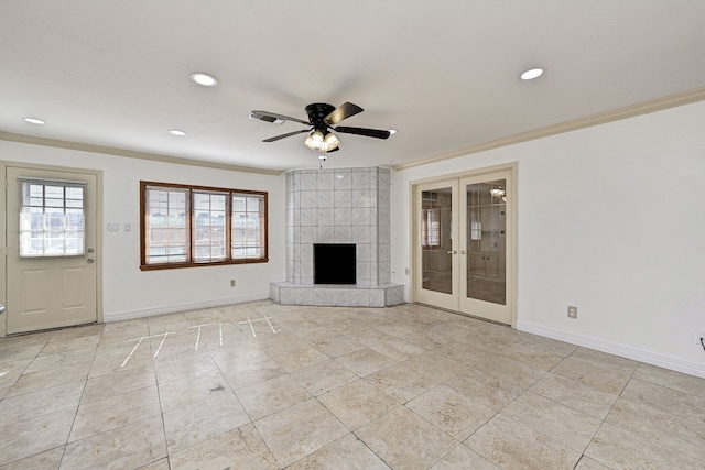 unfurnished living room featuring a tiled fireplace, crown molding, french doors, and ceiling fan