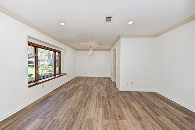 unfurnished room with hardwood / wood-style floors, crown molding, and a chandelier