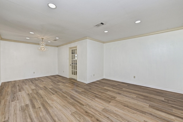 unfurnished room featuring hardwood / wood-style flooring, crown molding, and a chandelier