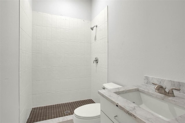 bathroom featuring tiled shower, vanity, and toilet