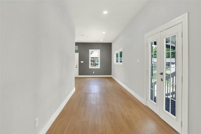 hallway with french doors and light hardwood / wood-style flooring