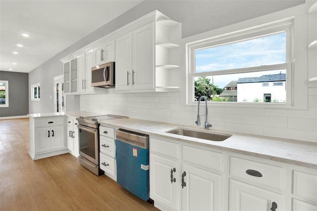 kitchen featuring sink, light stone countertops, appliances with stainless steel finishes, tasteful backsplash, and white cabinetry