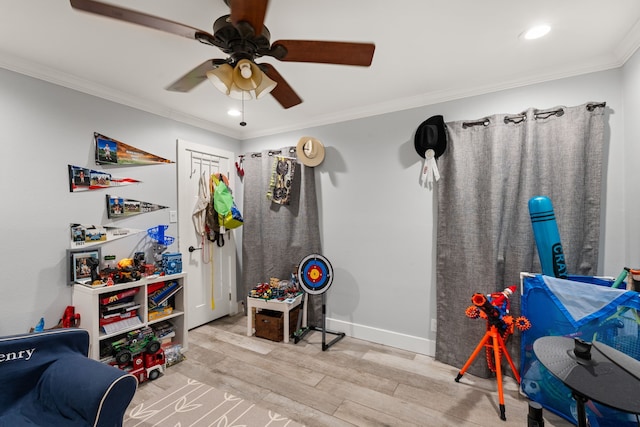 recreation room with crown molding, ceiling fan, and light hardwood / wood-style flooring