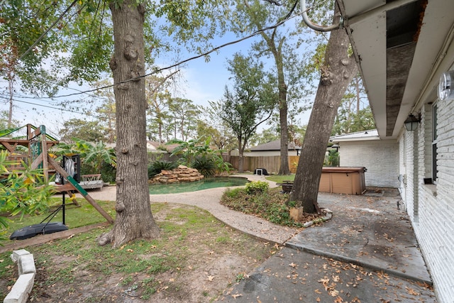 view of yard with a hot tub, a patio area, and a playground