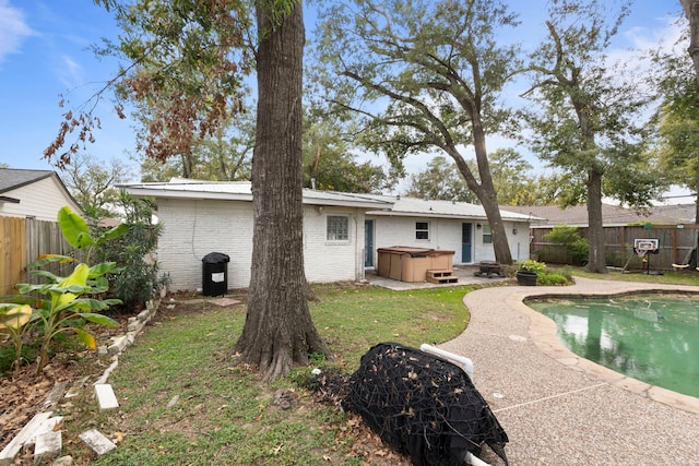 rear view of property featuring a pool with hot tub and a patio