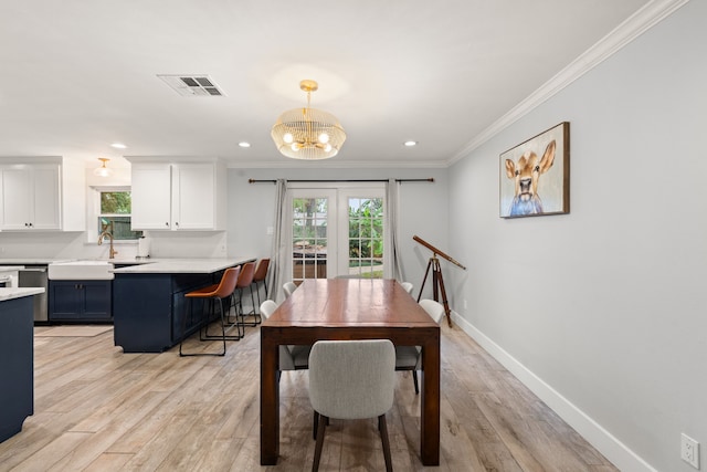 dining room featuring crown molding, light hardwood / wood-style floors, sink, and a wealth of natural light