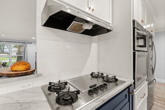 kitchen featuring blue cabinets, crown molding, appliances with stainless steel finishes, decorative backsplash, and white cabinets