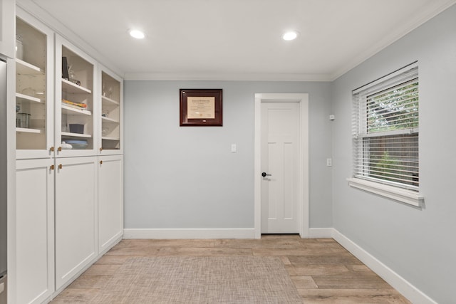 entryway with ornamental molding and light hardwood / wood-style floors