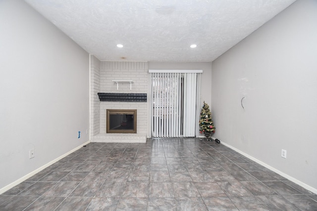 unfurnished living room featuring a textured ceiling and a brick fireplace