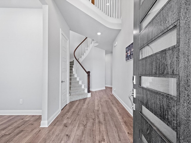 foyer with a towering ceiling, baseboards, stairway, and wood finished floors