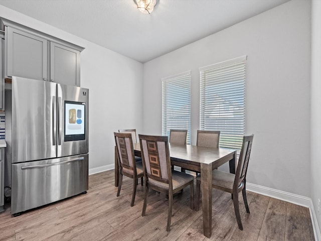 dining space with light wood finished floors and baseboards